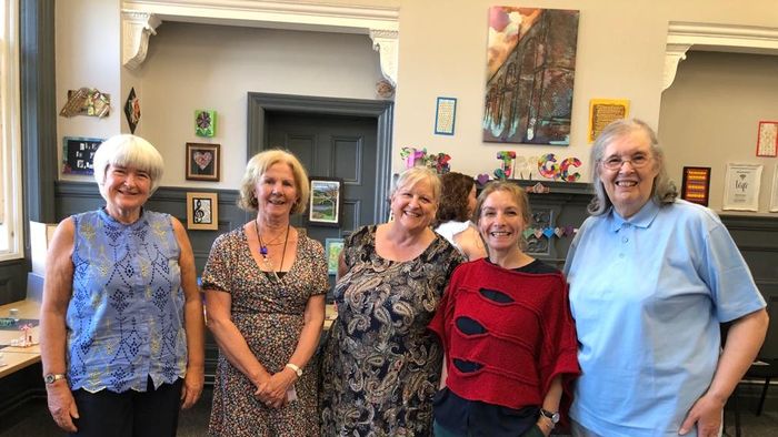 Photograph of workshop regulars with Mo Fox, together and smiling at the exhibition in June 2022.